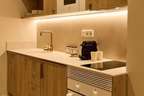 Moderna cocineta del hotel Arrels Mercat en Valencia con muebles de madera, encimera blanca y electrodomésticos de acero inoxidable
