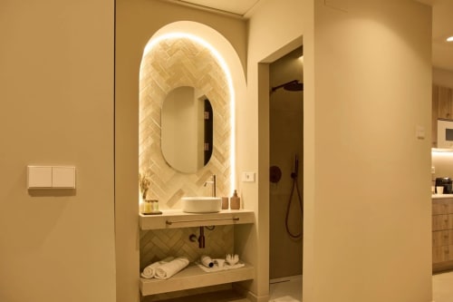 Lavabo moderno del hotel Arrels Mercat en Valencia con espejo ovalado iluminado y azulejos tipo espiga