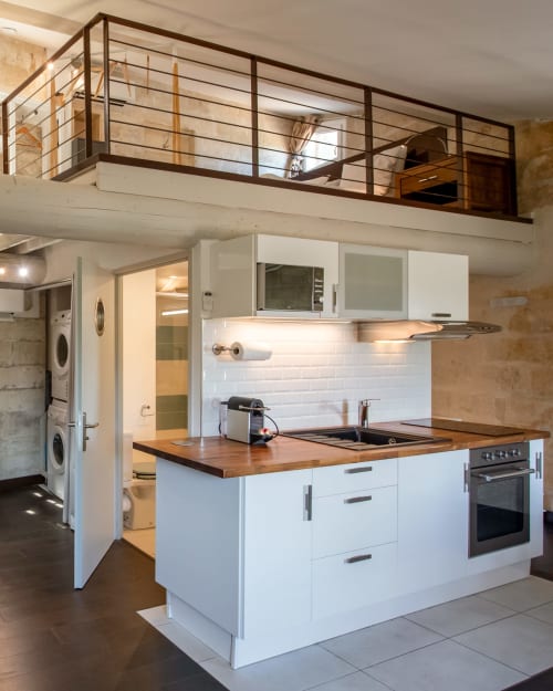 Cuisine moderne aux armoires blanches, plan de travail en bois et mezzanine dans l'appartement St Eloi, Villeneuve-les-Avignon