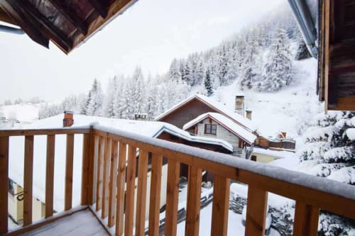 Vue alpine enneigée depuis la terrasse en bois du Chalet Savoyard à La Plagne Tarentaise, avec forêt de sapins