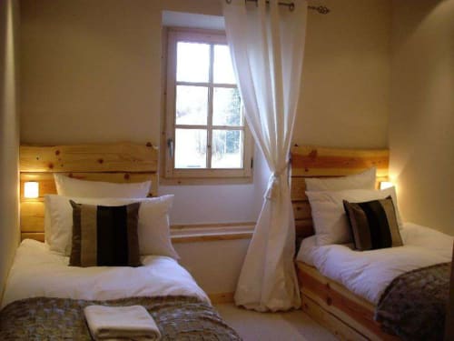 Chambre twin du Chalet Savoyard, La Plagne Tarentaise, avec têtes de lit en bois et vue sur les montagnes
