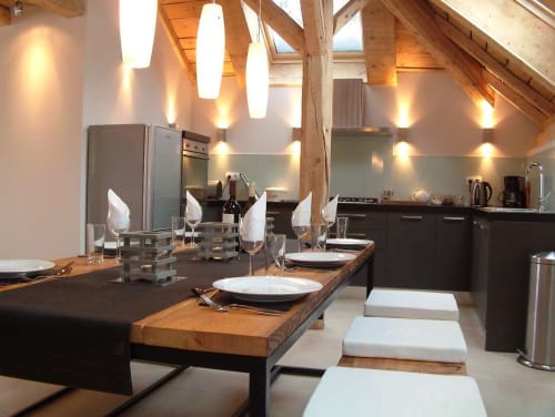 Cuisine ouverte et salle à manger du Chalet Savoyard avec poutres en bois, luminaires suspendus et table élégante