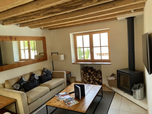 Salon rustique moderne du gîte Le Chalet Savoyard à La Plagne avec poutres apparentes, cheminée et vue sur les montagnes