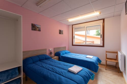 Habitación doble con dos camas azules en el Hostal A Taberna de Vento de Lalín, España