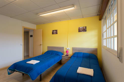 Luminoso dormitorio doble con dos camas azules en Hostal A Taberna de Vento en Lalín, España