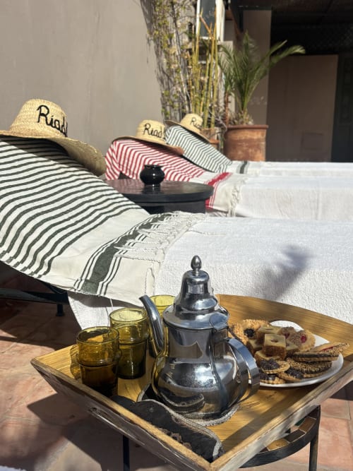 Service à thé marocain traditionnel au Riad 191 Marrakech avec chapeaux de paille, linges rayés et pâtisseries sur plateau en bois