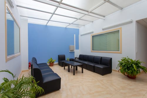 Moderna zona de descanso en el Hostal A Taberna de Vento, Lalín, con asientos negros, pared azul y luz natural