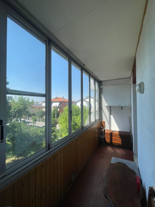 Balcone luminoso e rivestito con vista sulla città a Forlì, ringhiere in legno, finestre moderne