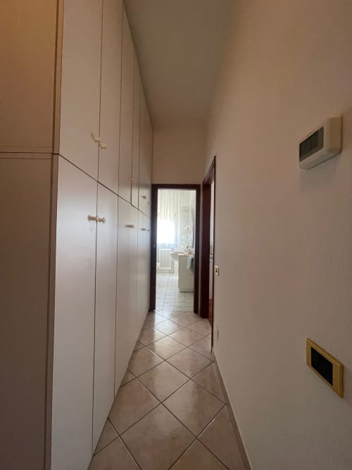 Corridoio dell'appartamento LHE Street Forlì con armadi a muro, pavimento in piastrelle, termostato e accesso aperto verso la cucina