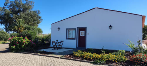White cottage apartment with garden view at Monte da Morena in Serpa, Portugal, featuring patio seating and landscaped