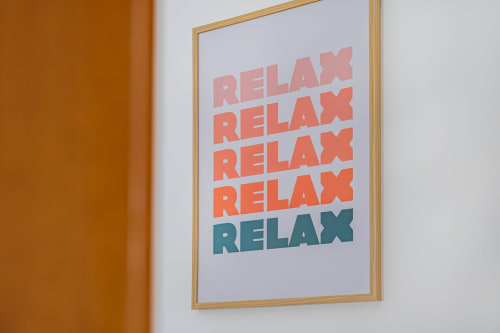 Pôster motivacional moldado exibindo texto 'RELAX' em cores degradê no hotel Signature Stays