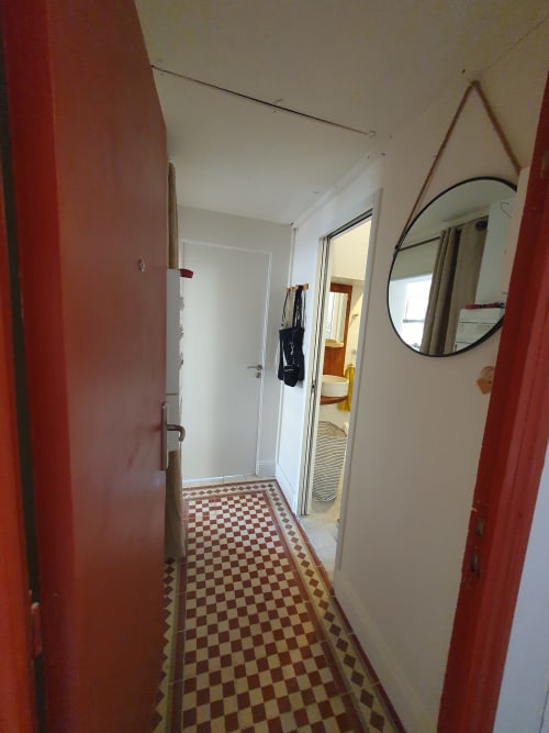 Couloir du Mas des Ecoliers Provence B&B avec portes rouges, carrelage à damier et miroir circulaire