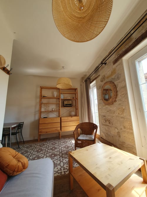 Salon lumineux du Mas des Ecoliers avec meubles en rotin, mobilier bois et murs en pierre naturelle