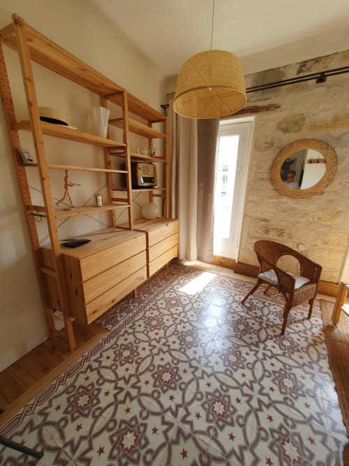 Chambre provençale avec mobilier en bois, luminaire suspendu tissé et carrelage à motifs au Mas des Ecoliers