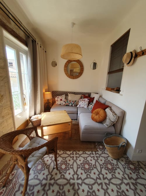 Salon cosy provençal au Mas des Écoliers avec canapé gris, détails en osier et lumière naturelle