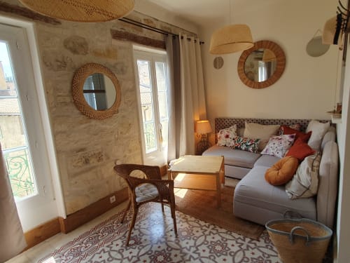 Chambre provençale cosy du Mas des Ecoliers avec murs en pierre, miroirs tissés et coin salon près des portes-fenêtres