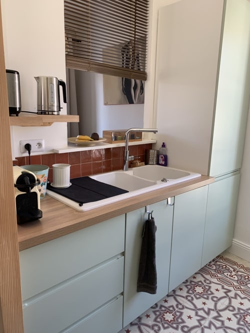 Petite cuisine moderne aux armoires blanches, plan de travail en bois et dosseret de carreaux rouges au Mas des Ecoliers, Châteaurenard