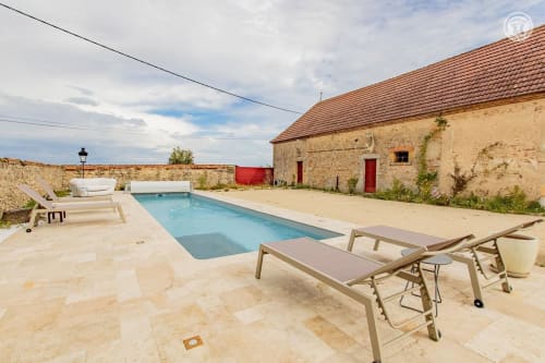 Piscine et chaises longues à Au 3 Cyprès de Précy, chambre d'hôtes à Neuvy Grandchamp, bâtisse en pierre.