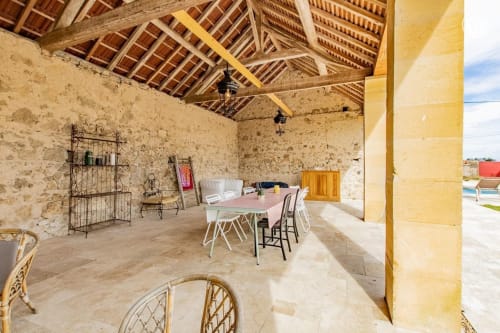 Terrasse couverte aux murs en pierre rustique et poutres en bois à Au 3 Cyprès de Précy, une maison d'hôtes en Bourgogne