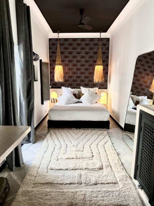 Chambre moderne au Riad 191 Marrakech avec literie blanche, tête de lit à motifs, luminaires suspendus et tapis géométrique