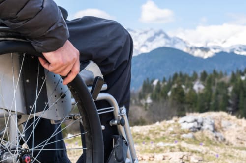 Persona che regola i freni della mountain bike con le vette alpine e le foreste di Locana sullo sfondo