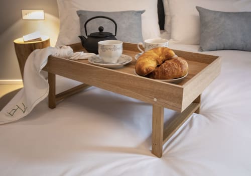 Vassoio in legno con colazione a letto presso Camere d'Aria B&B a Locana: pasticcini, tè e bollitore nero