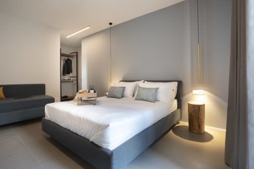 Camera moderna a Camere d'Aria B&B a Locana con biancheria bianca, letto con struttura scura, luci a sospensione e design minimalista.