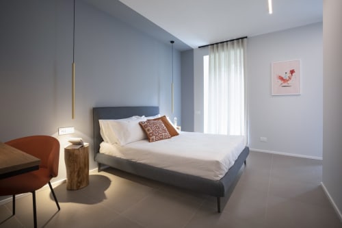 Camera moderna a Camere d'Aria B&B a Locana con letto grigio, biancheria bianca, lampada a sospensione e arredamento minimalista