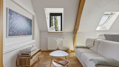 Appartement mezzanine moderne avec canapé gris, accents bois, puits de lumière et vue sur le jardin à L'etoile De Forges BnB