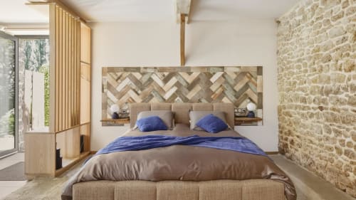Luxury bedroom at L'etoile De Forges with herringbone wood headboard, blue pillows, stone accent wall, and garden view in
