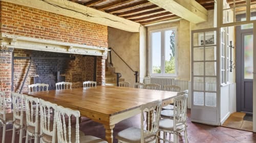 Spacieuse salle à manger avec table en bois, cheminée et vue sur le jardin du gîte L'Étoile De Forges à Longmesnil