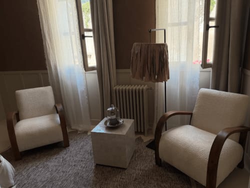 Coin salon élégant de la Maison Romy BnB avec deux fauteuils crème, guéridon et fenêtres donnant sur la ville