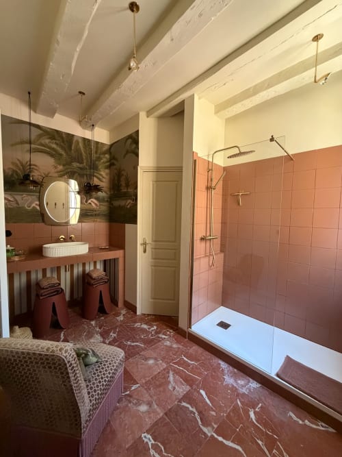 Salle de bain luxueuse de la Maison Romy B&B avec carrelage en terre cuite, douche pluie et papier peint botanique