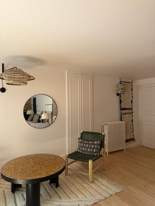 Chambre Balthazar à la Maison Romy B&B avec miroir rond, chaise tissée, table en chevrons et vue sur la ville