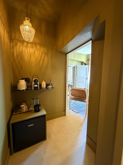 Couloir jaune moutarde de la Maison Romy B&B avec luminaire suspendu, étagères et accès à la chambre