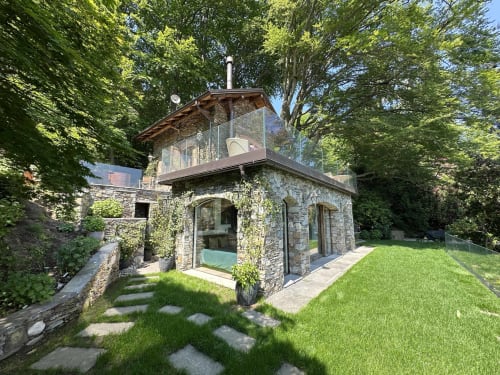 Moderne Steinvilla mit verglaster Oberer Terrasse im luxuriösen Spa-Resort in Stresa, Italien, umgeben von grünem Rasen und alten Bäumen