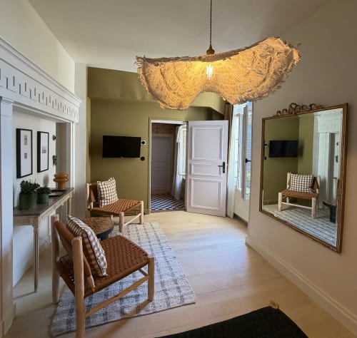 Chambre paisible à la Maison Romy B&B avec suspension tressée, chaises en bois, miroir et vue sur le jardin