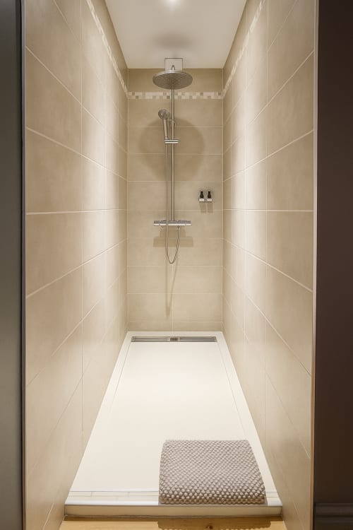 Salle d'eau contemporaine avec carrelage beige, pluie de tête et vasque blanche à l'hôtel Maunoury Citybreak à Chartres