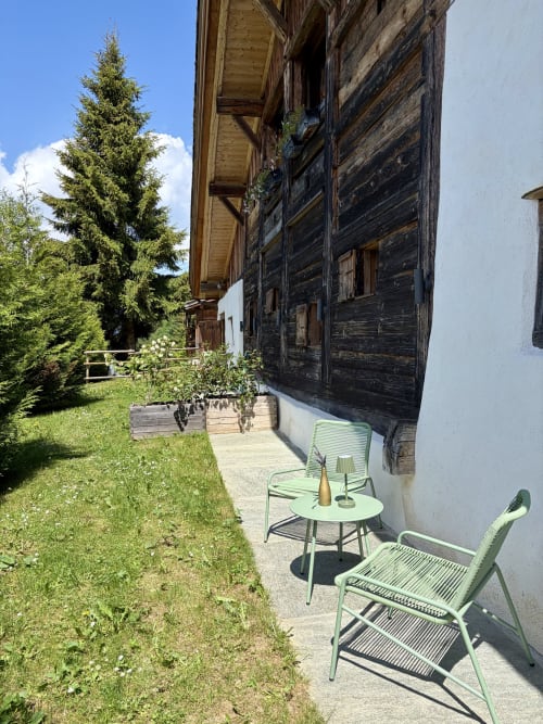 Terrasse extérieure de la Ferme 1828 B&B à Demi-Quartier avec chaises vert menthe et vue sur les montagnes