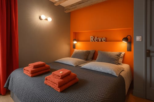 Chambre moderne à Maunoury Citybreak à Chartres avec mur d'accent orange, lit double, literie grise et serviettes orange