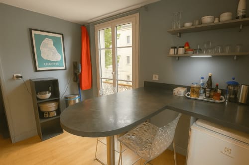 Cuisine moderne dans un appartement à Chartres avec comptoirs gris, coin repas et vue sur le jardin par les portes-fenêtres