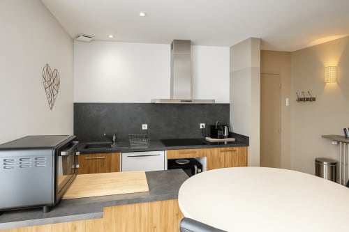 Cuisine moderne dans un appartement 2 chambres à Maunoury Citybreak Chartres avec plan de travail noir, meubles en bois et inox