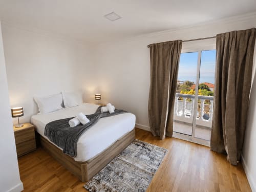 Quarto moderno com vista para o mar na villa Atlantic Escape 1, Funchal. Cama de casal, pisos de madeira, acesso à varanda.