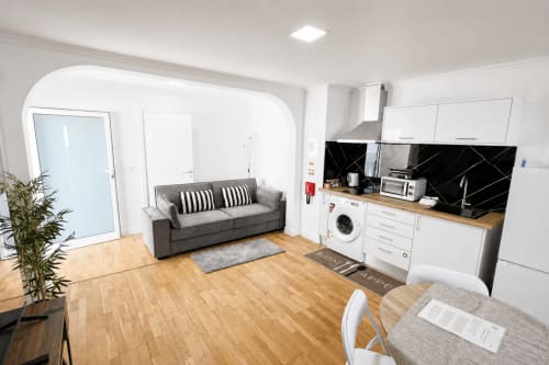 Villa moderna com planta aberta no Funchal, sofá cinzento, cozinha, sala de jantar e pavimento de madeira