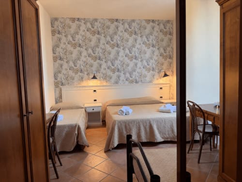 Spaziosa camera da letto al Villino Gregoraci Relais di Santa Marinella con due letti, carta da parati floreale e vista mare