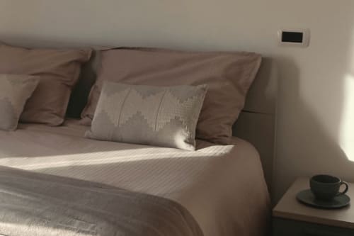 Camera da letto serena della Gentle Home Collection di Accettura con cuscini marroni, biancheria bianca e tazza di caffè sul comodino.