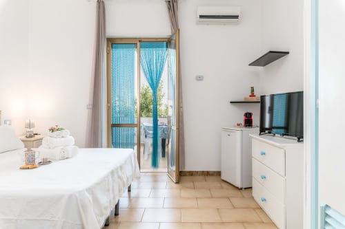 Luminoso monolocale a Il Porticciolo Vacanze con balcone vista mare, TV a schermo piatto, angolo cottura e arredi bianchi