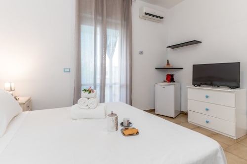 Camera luminosa con vista mare presso Il Porticciolo Vacanze, letto bianco, TV, frigobar e aria condizionata