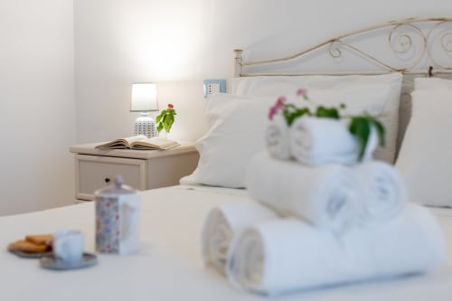 Camera accogliente a Il Porticiolo Vacanze con vista mare, biancheria bianca, comodino con lampada e fiori freschi