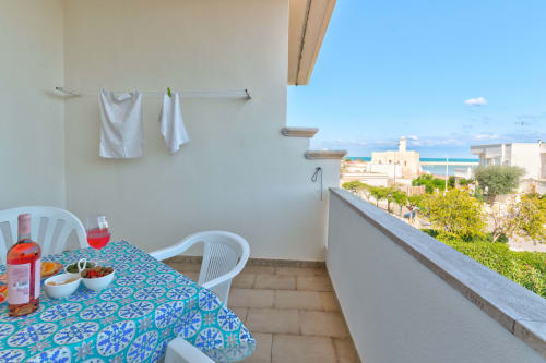 Balcone soleggiato con vista mare a Il Porticicolo Vacanze, Villanova. Tavolo da pranzo con tovaglia a motivi, sedie bianche